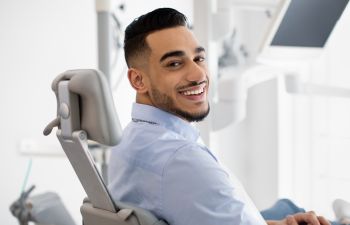 A satisfied smiling young man in a dental chair.